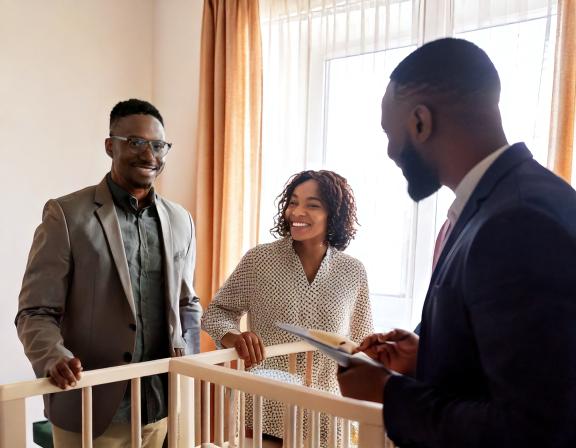 Firefly man and woman standing behind a crib and smiling, talking to a man who is holding a clipboard (1)