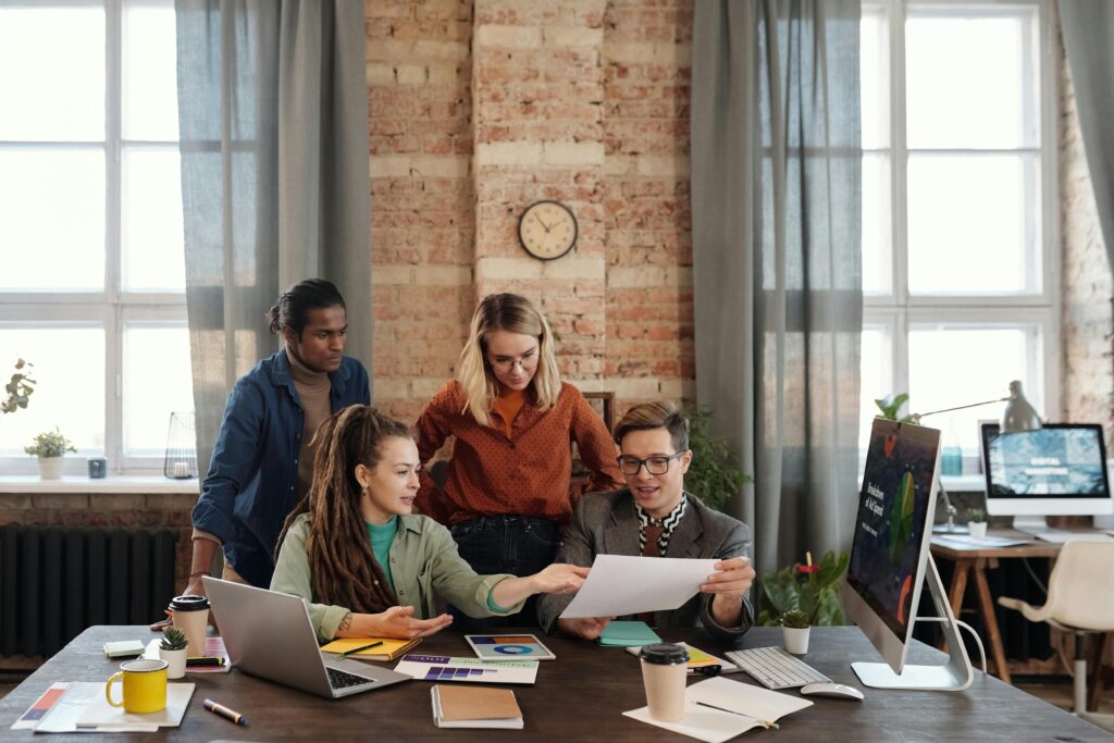 A group of people gather around a desk to discuss an idea.